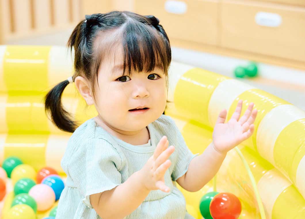 スプーンを持って食事をする乳児