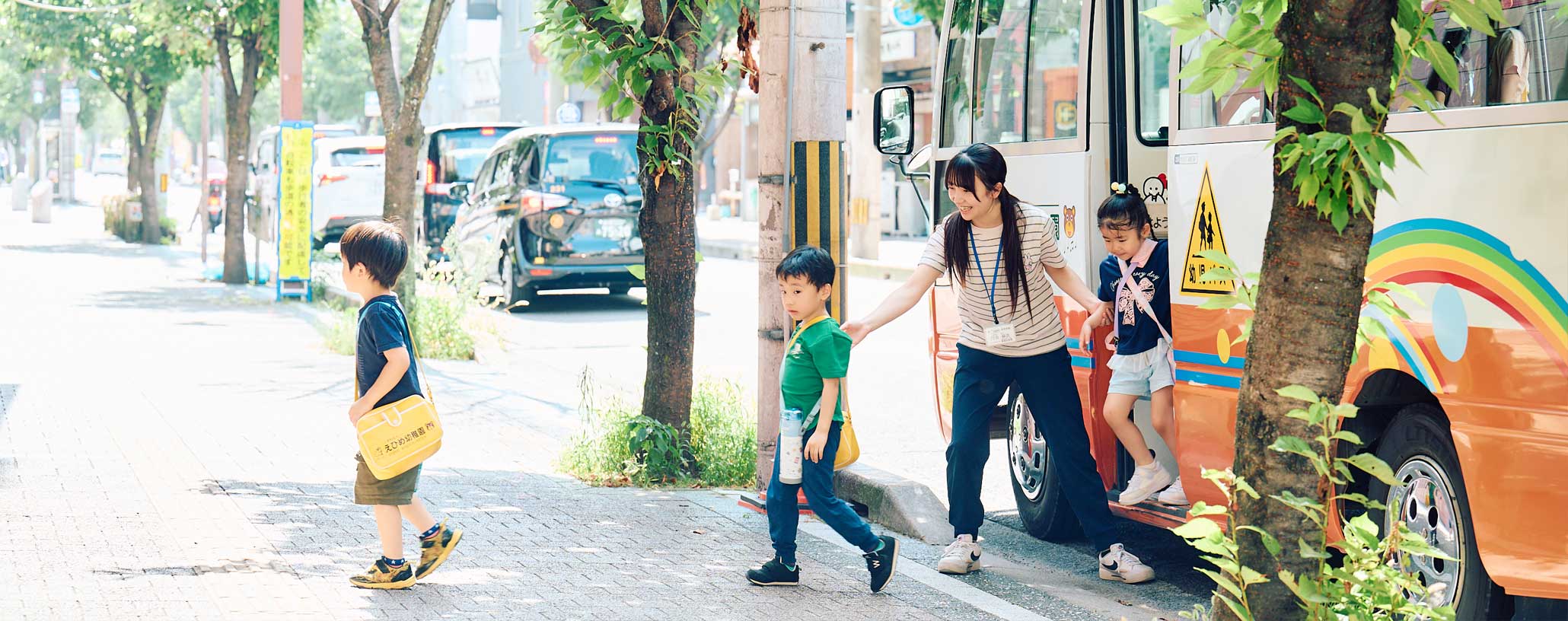 スクールバスに乗り込む子どもたちと、乗車を確認する職員