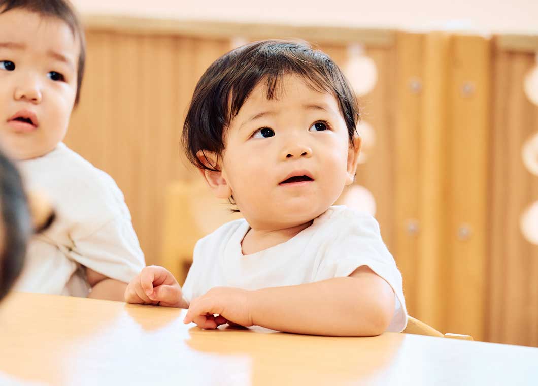 スプーンを持って食事をする乳児